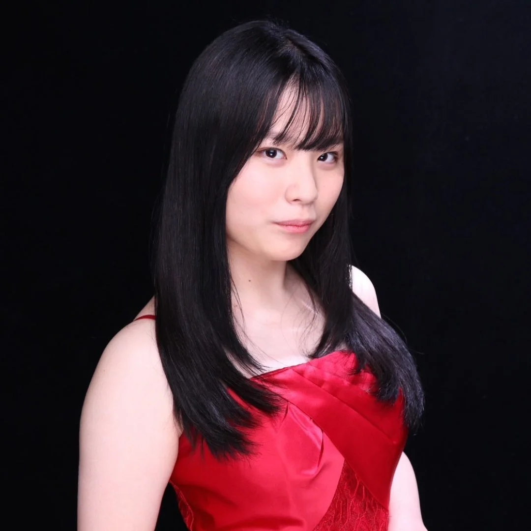 黒い背景の前で、赤いドレスを着用した黒髪の若い日本人女性のポートレート